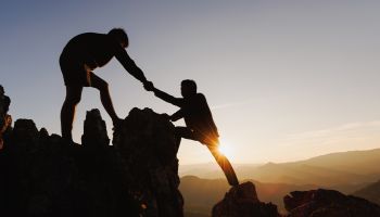 Photo of a mountain climber helping another mountain climber to illustrate the article 