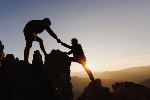 Photo of a mountain climber helping another mountain climber to illustrate the article 