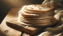 Photo of a stack of round flat bread on a wooden table to illustrate the article “I Am the Bread of Life.”