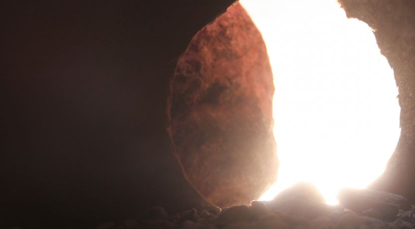 View from inside a tomb looking toward a round opening with the round stone door mostly rolled back. This illustrates the article 