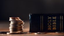 Photo of a stack of coins next to a Bible, to illustrate the article You Cannot Serve God and Money